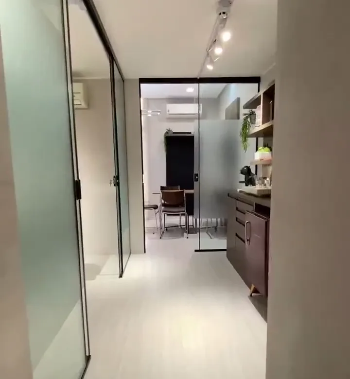 Sala privativa do UNA Coworking com mesa clara, cadeiras pretas e divisória de vidro.