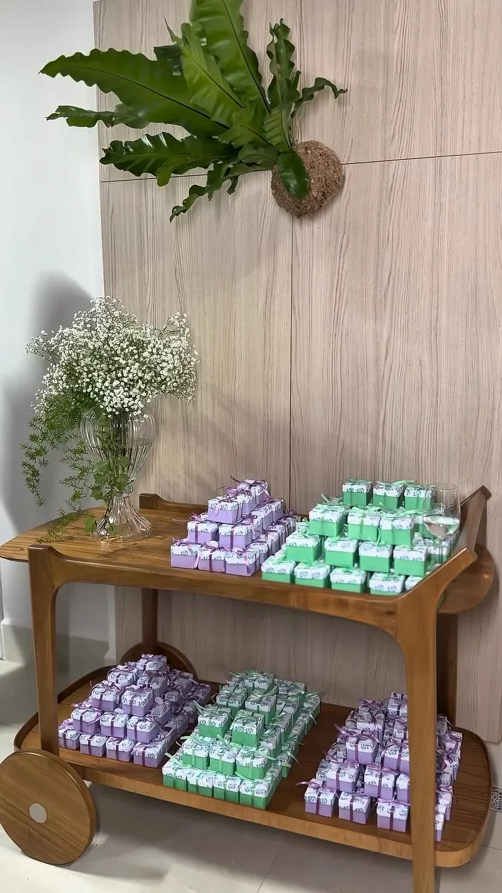 Painel de madeira com samambaia, vaso de flores brancas e carrinho de madeira.